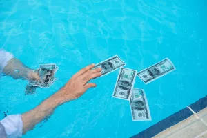 Cost to Epoxy Paint a Pool Deck - Person Grabbing Money in Pool