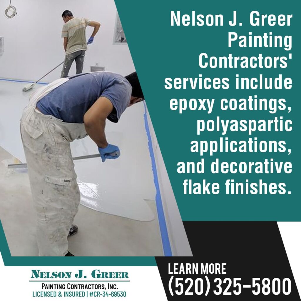 Two painters applying a floor coating, with a focus on one painter using a roller near a blue-taped edge.